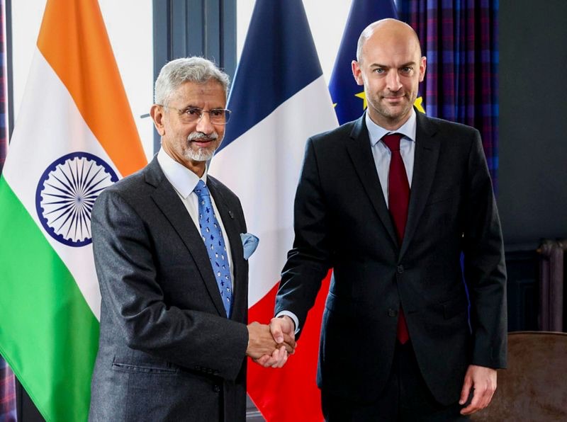 Dr. S. Jaishankar shaking hands with his French counterpart in front of Indian, French and European Union flags