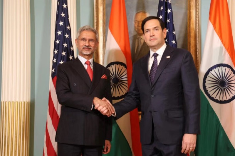 Dr. S. Jaishankar and US Secretary of State Marco Rubio shaking hands in front of Indian and US flags