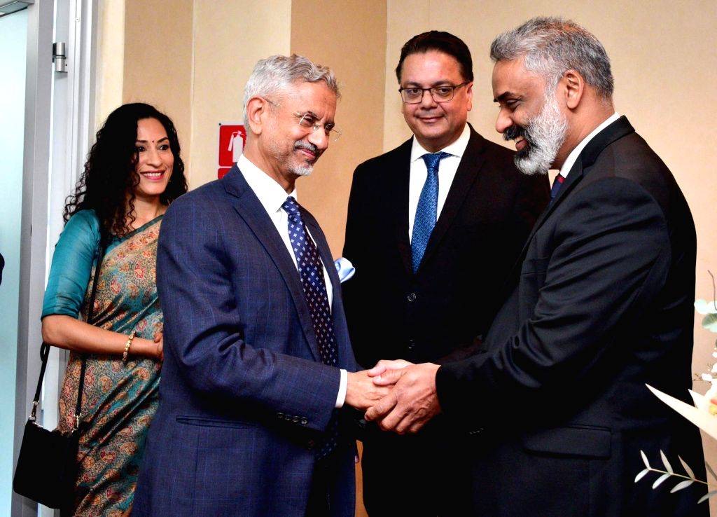 Dr. S. Jaishankar clasping hands with a bearded official while others look on, in a corridor