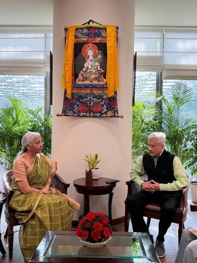 Dr. S. Jaishankar seated in conversation with a colleague in a sari, beneath a Tibetan thangka painting