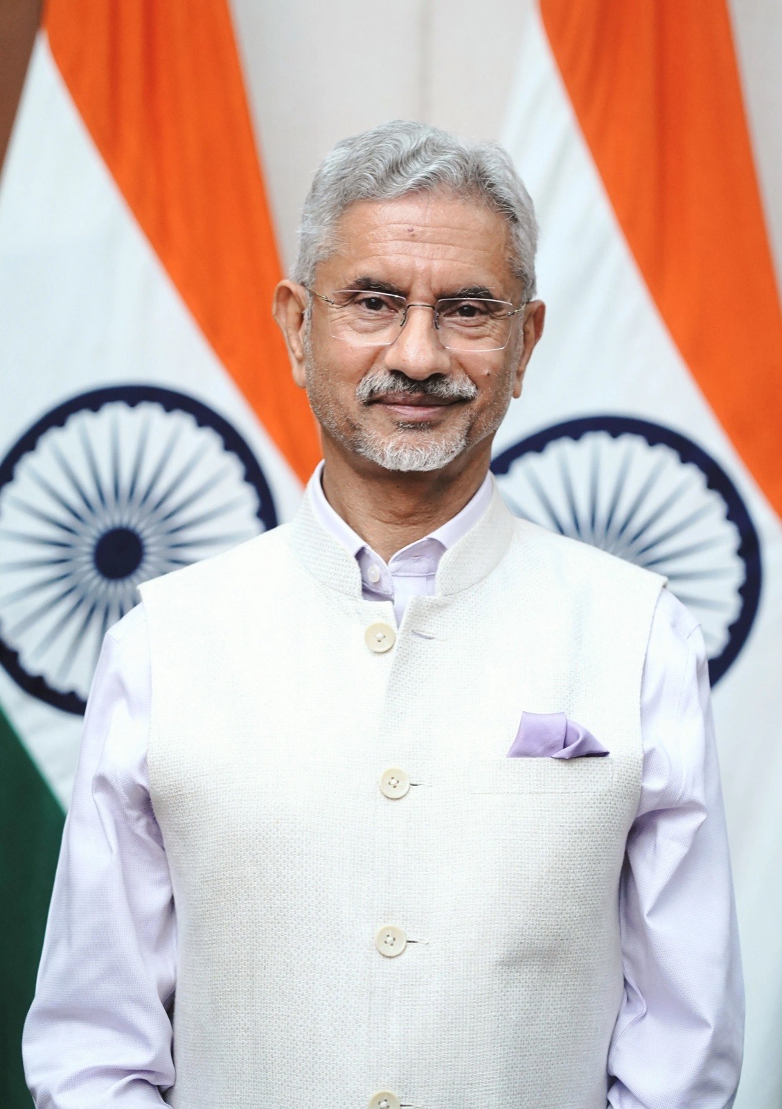 Portrait of Dr. S. Jaishankar in a white bandhgala jacket, standing in front of Indian national flags