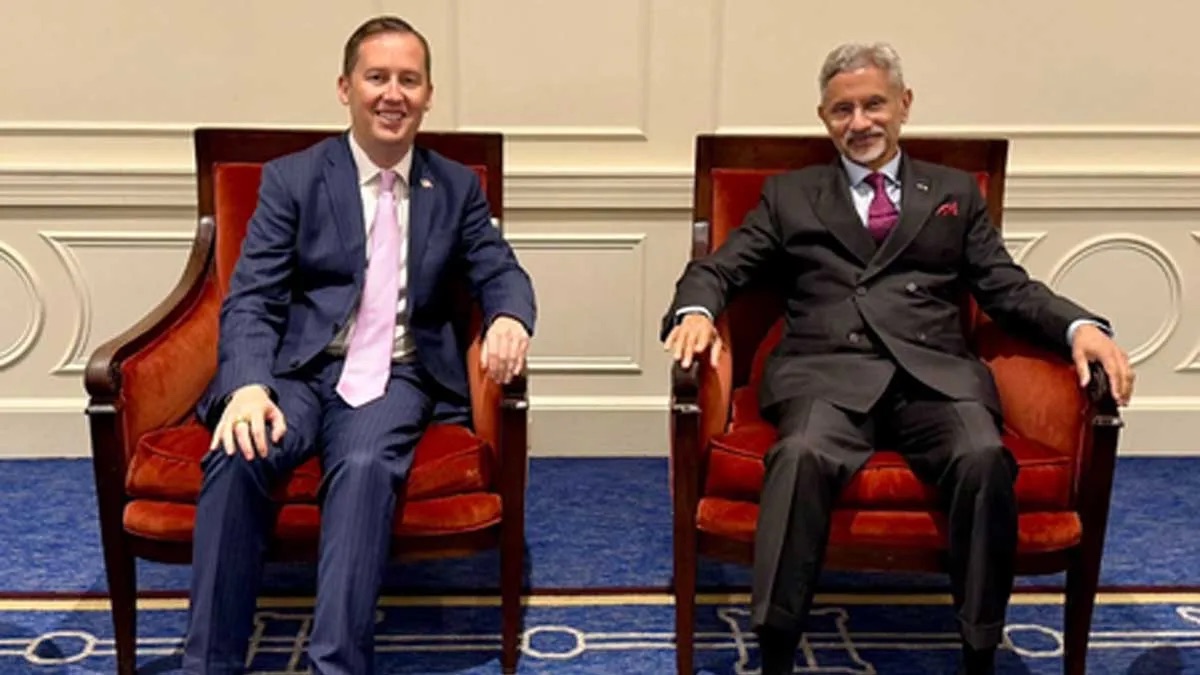 Dr. S. Jaishankar seated in a formal armchair beside a US official in a reception room with a blue patterned carpet